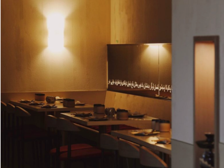 A gold-lit restaurant interior with moody lighting and tables. 